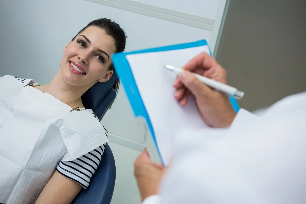 doctor-writing-clipboard-while-patient-lying-dental-bed 1