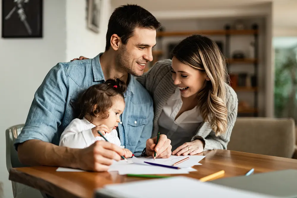 jovens-pais-felizes-desfrutando-de-colorir-com-sua-filha-pequena-em-casa
