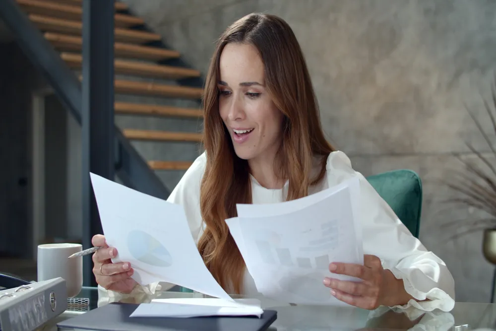 resized_joyful-business-lady-analyzing-financial-report-smiling-woman-working-office