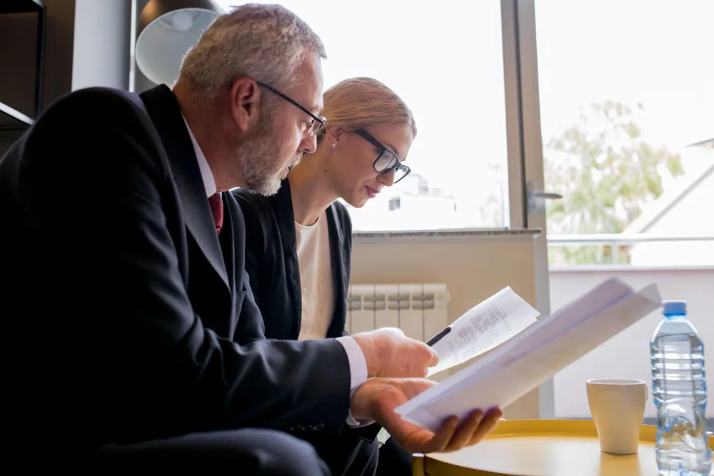 resized_portrait-business-man-woman-sitting-office-discussing-contract
